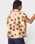 Woman wearing a beige floral-patterned vest on a plain background