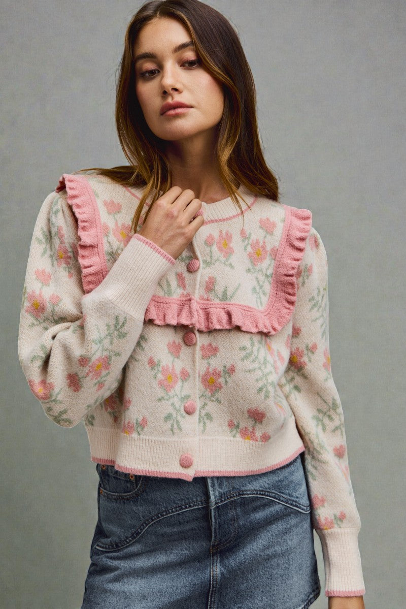 Woman wearing a floral blouse with pink ruffles and denim skirt on a gray background