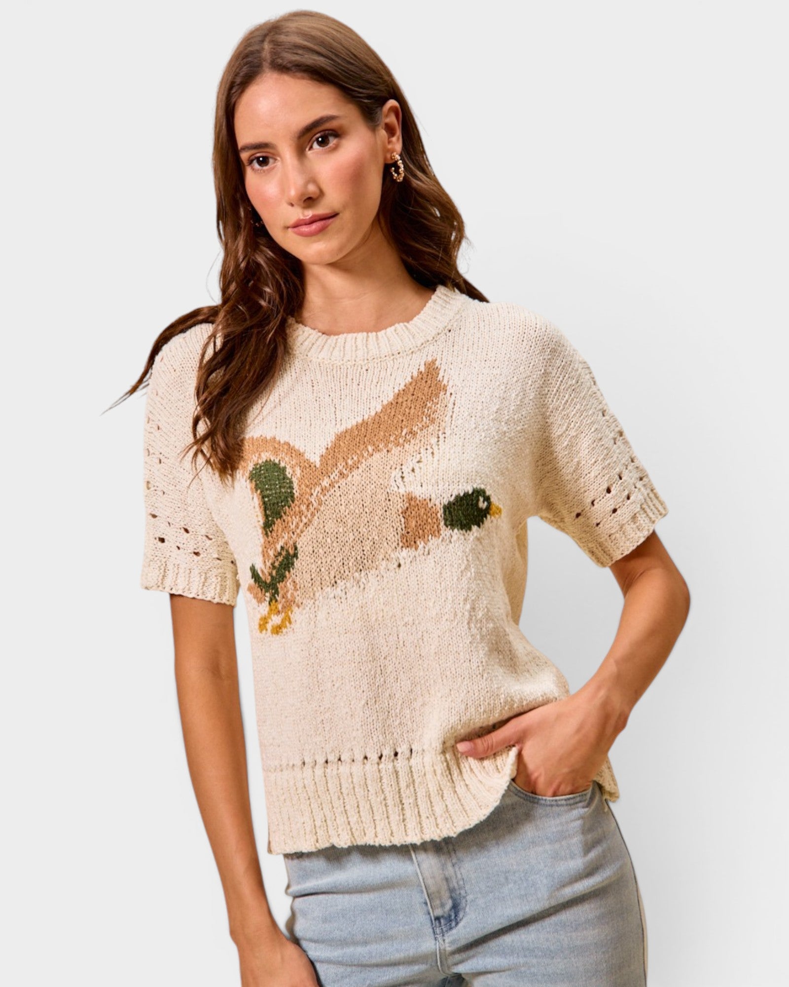 Woman wearing a beige sweater with a fox design on a light gray background