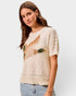 Woman wearing a beige sweater with a fish design on a plain background