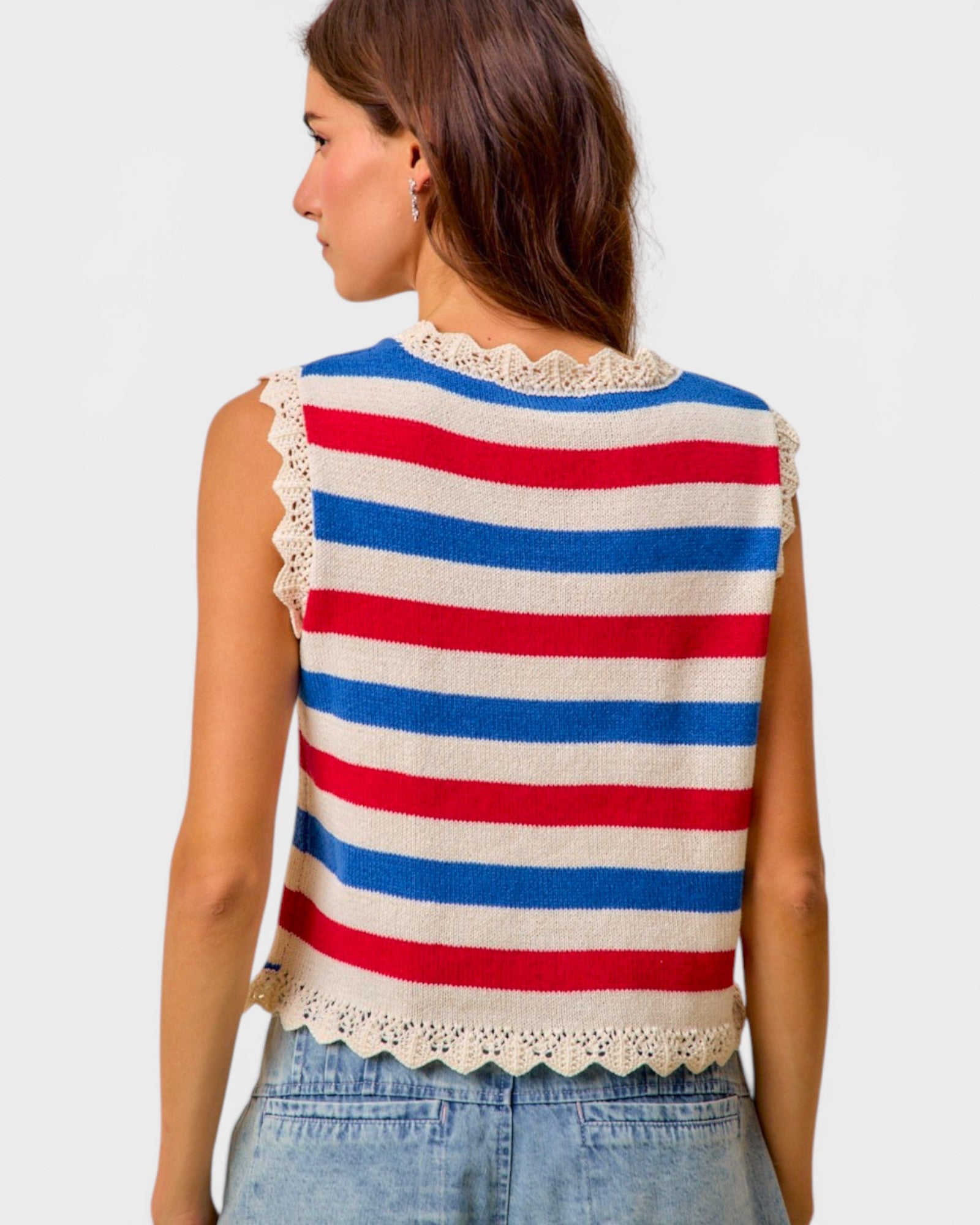 Woman wearing a sleeveless striped top with red, white, and blue colors on a plain background.
