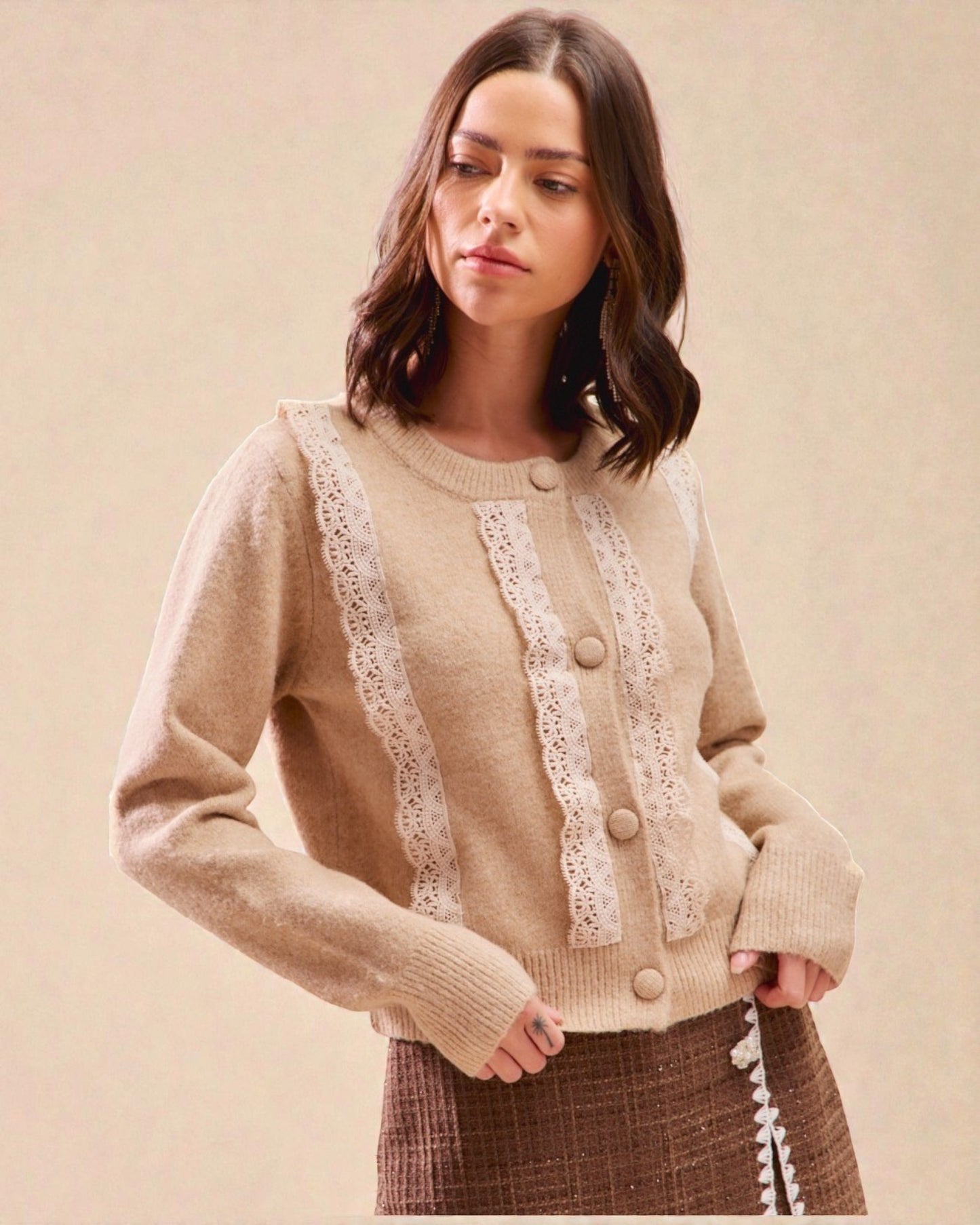 Woman wearing a beige sweater with lace details on a beige background