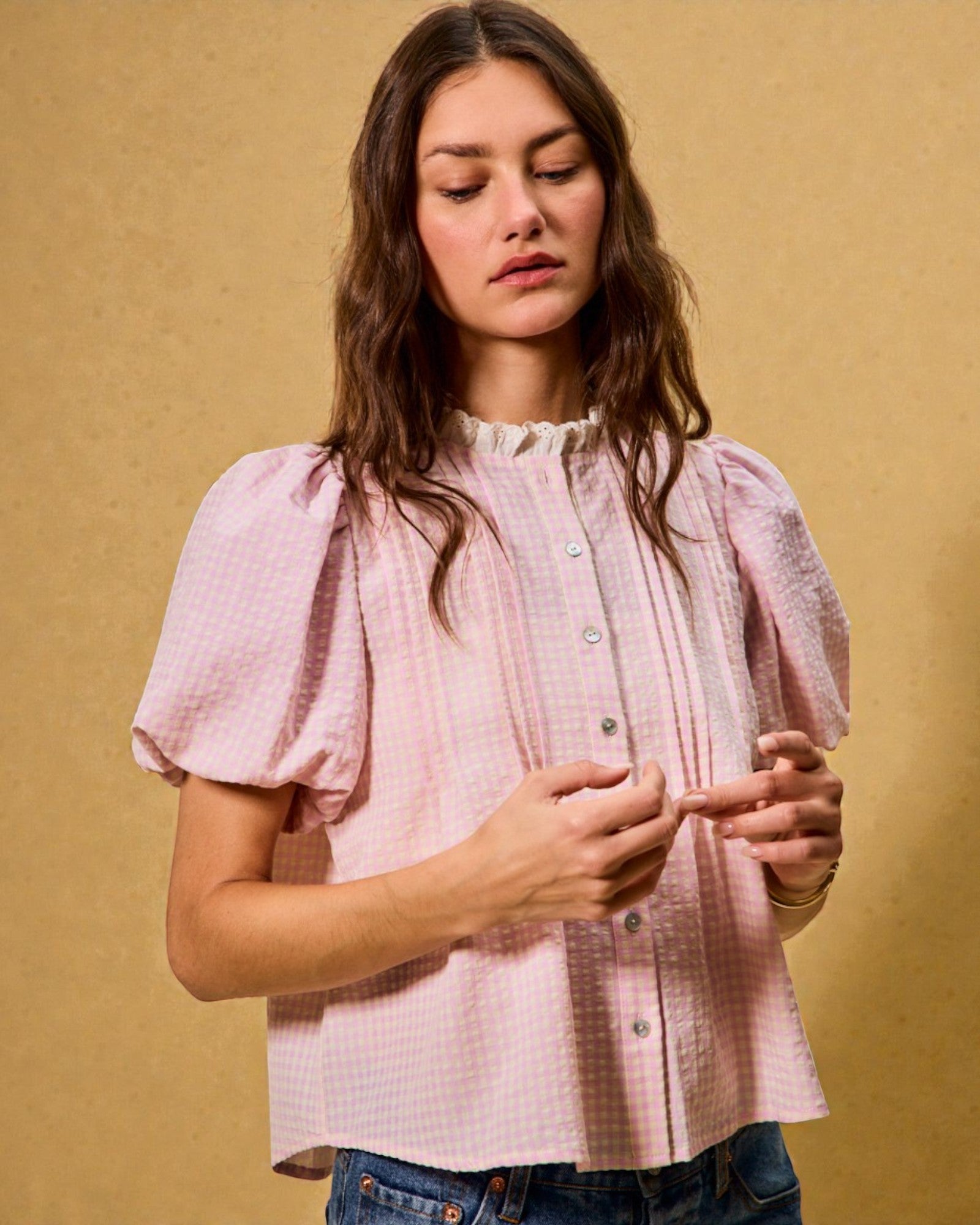 Woman wearing a pink checkered blouse against a beige background