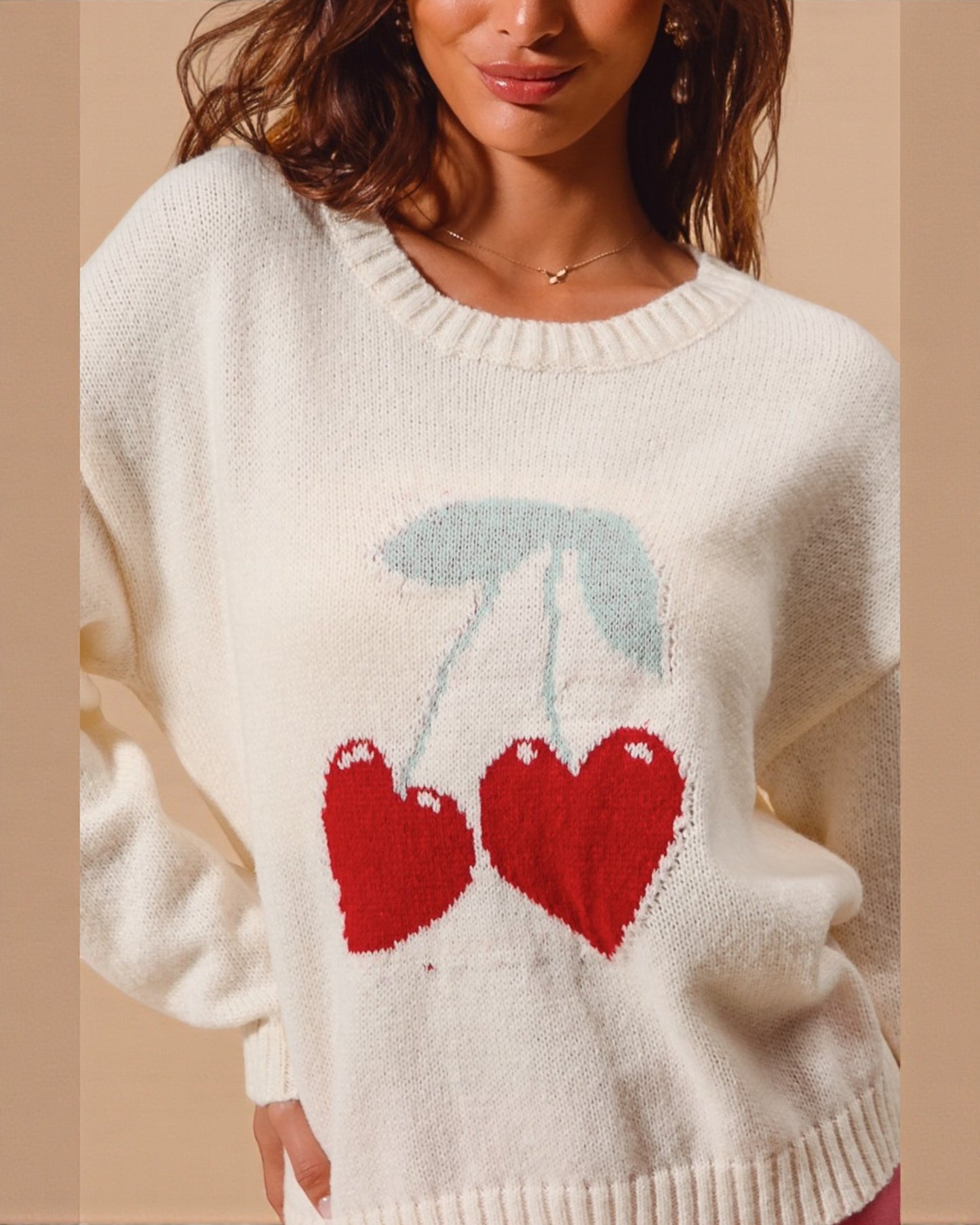 White sweater with red cherries and blue leaves on a beige background