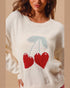 White sweater with red cherries and blue leaves on a beige background