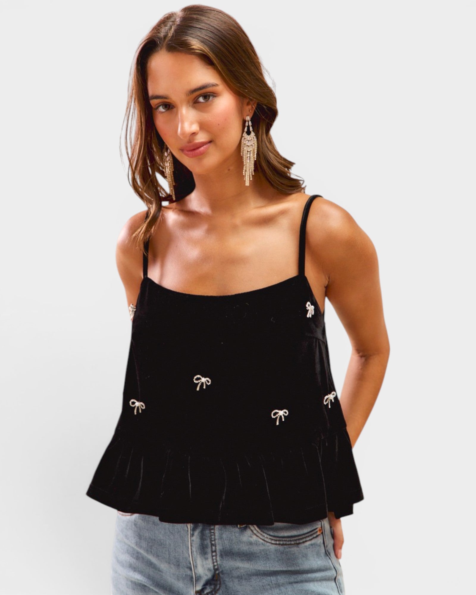 Woman wearing a black top with bow details on a white background
