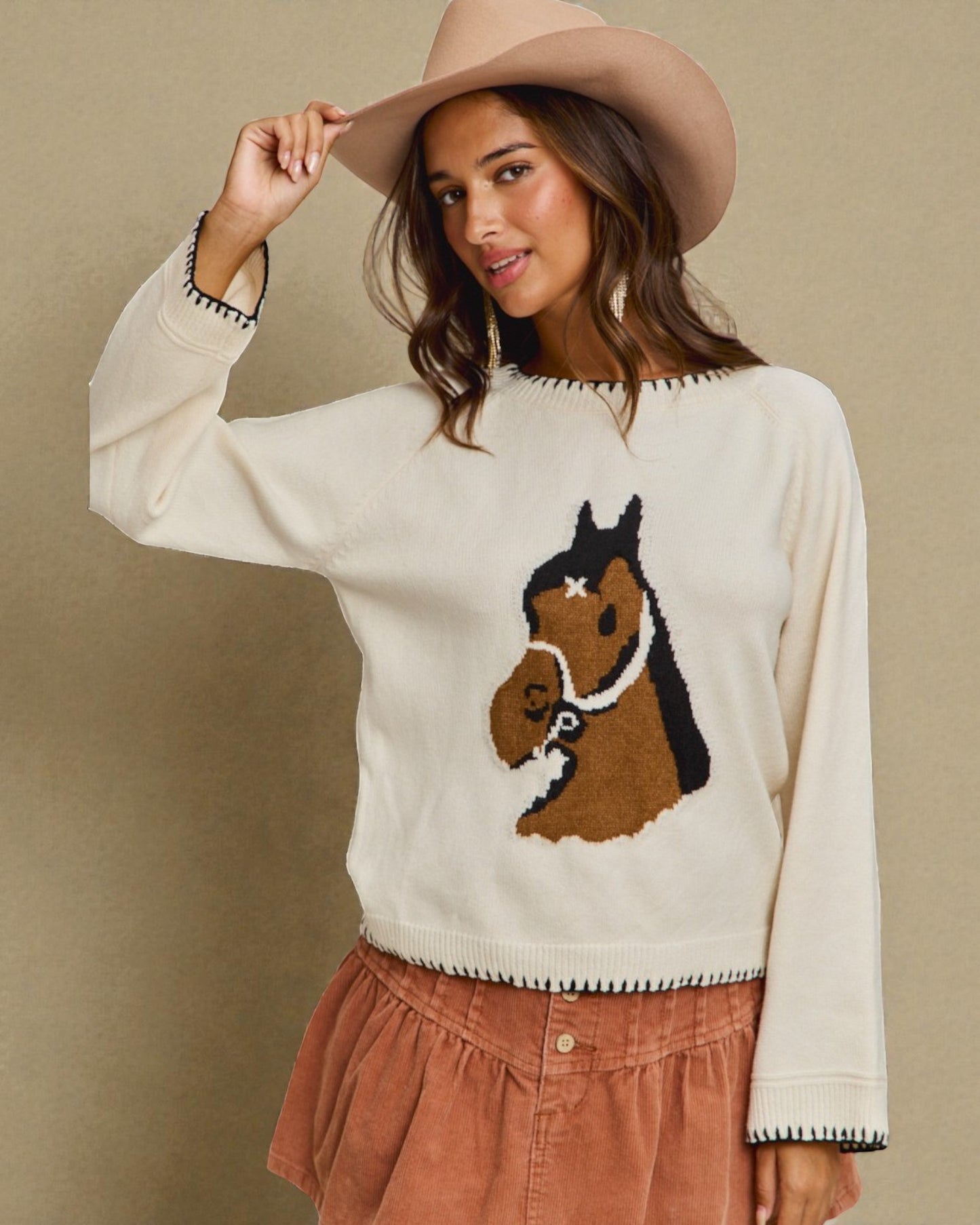 Woman wearing a sweater with a horse design against a beige background