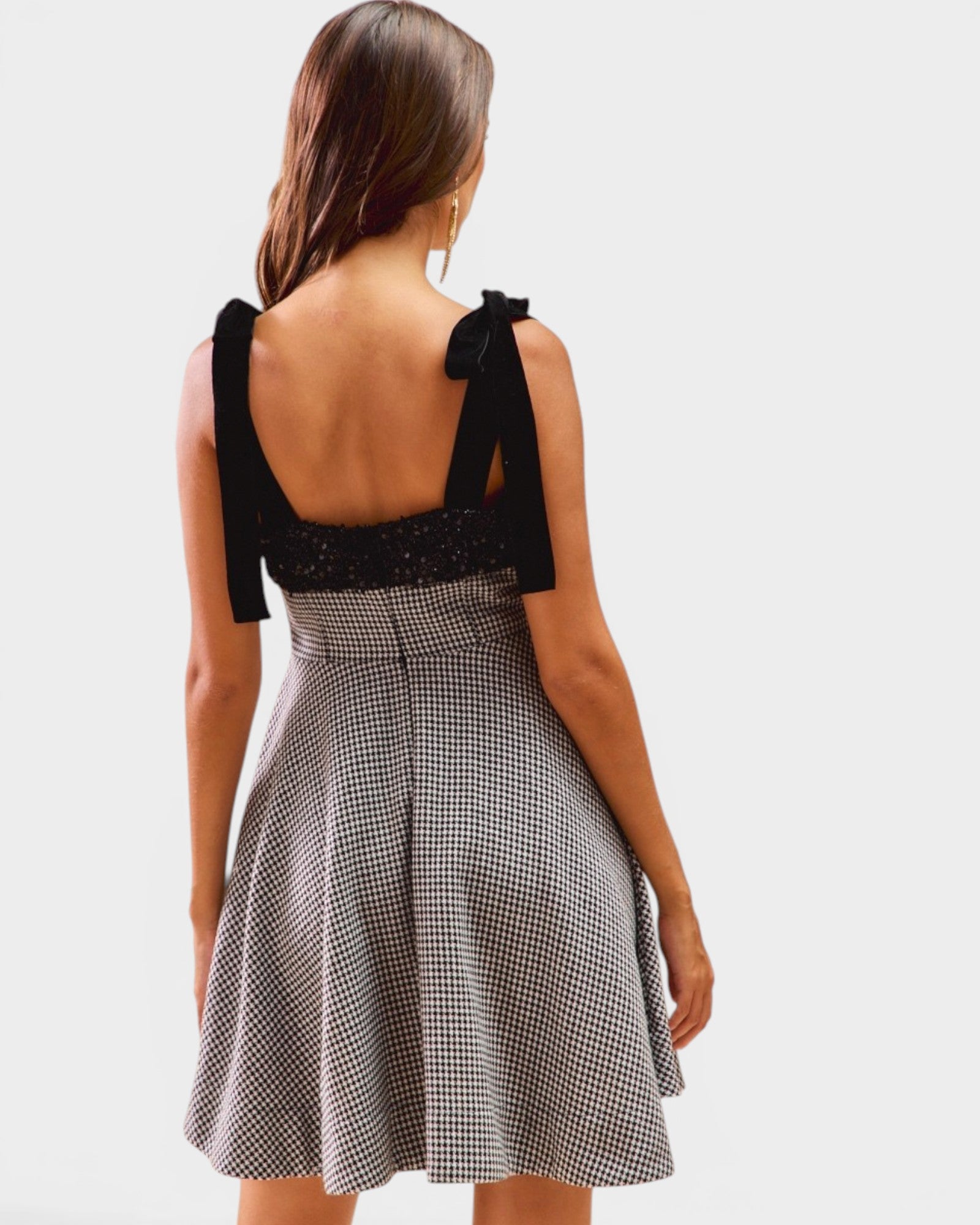 Woman wearing a black top and checkered skirt on a white background