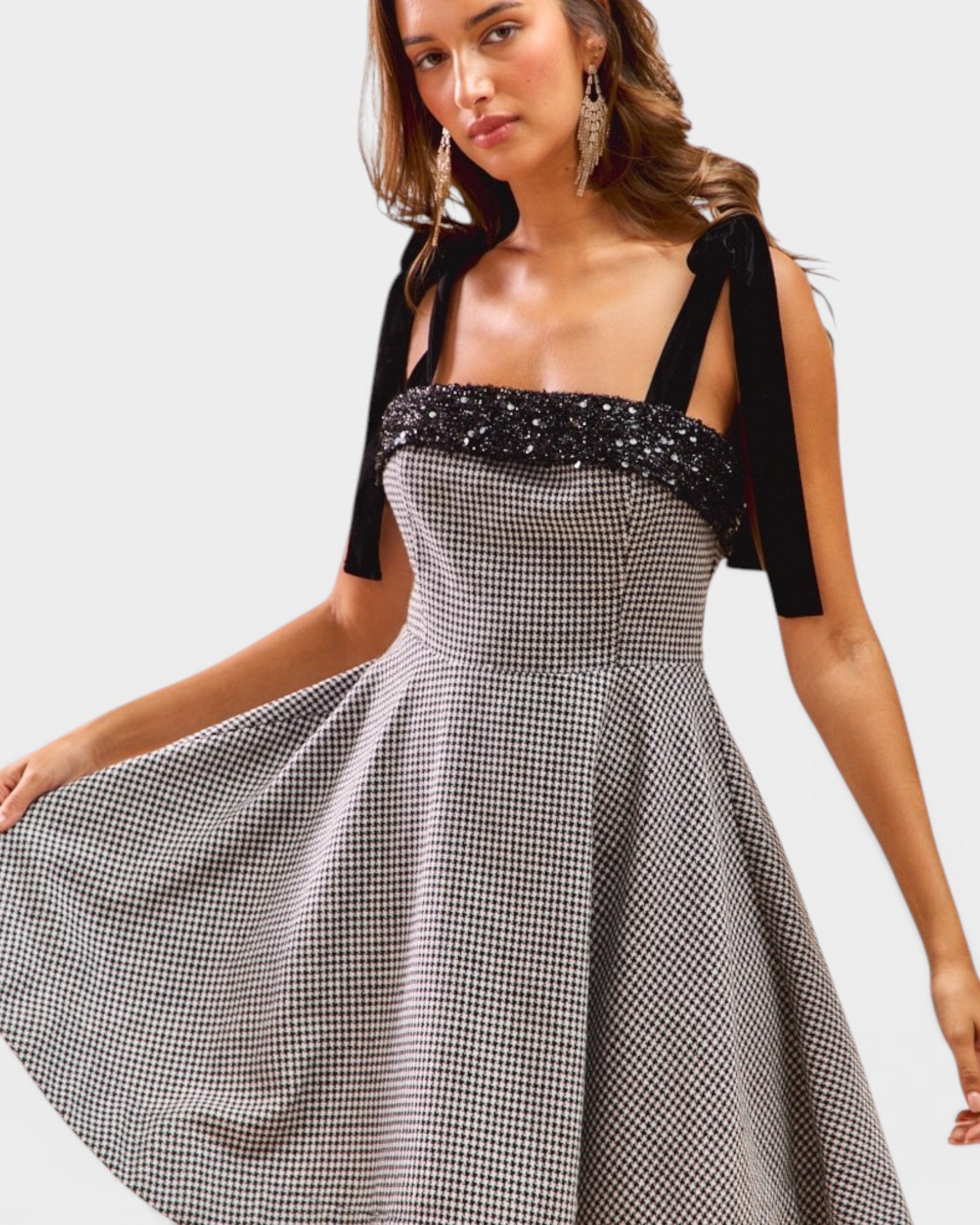 Woman wearing a black and white checkered dress with a black top on a white background