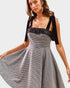Woman wearing a black and white checkered dress with a black top on a white background