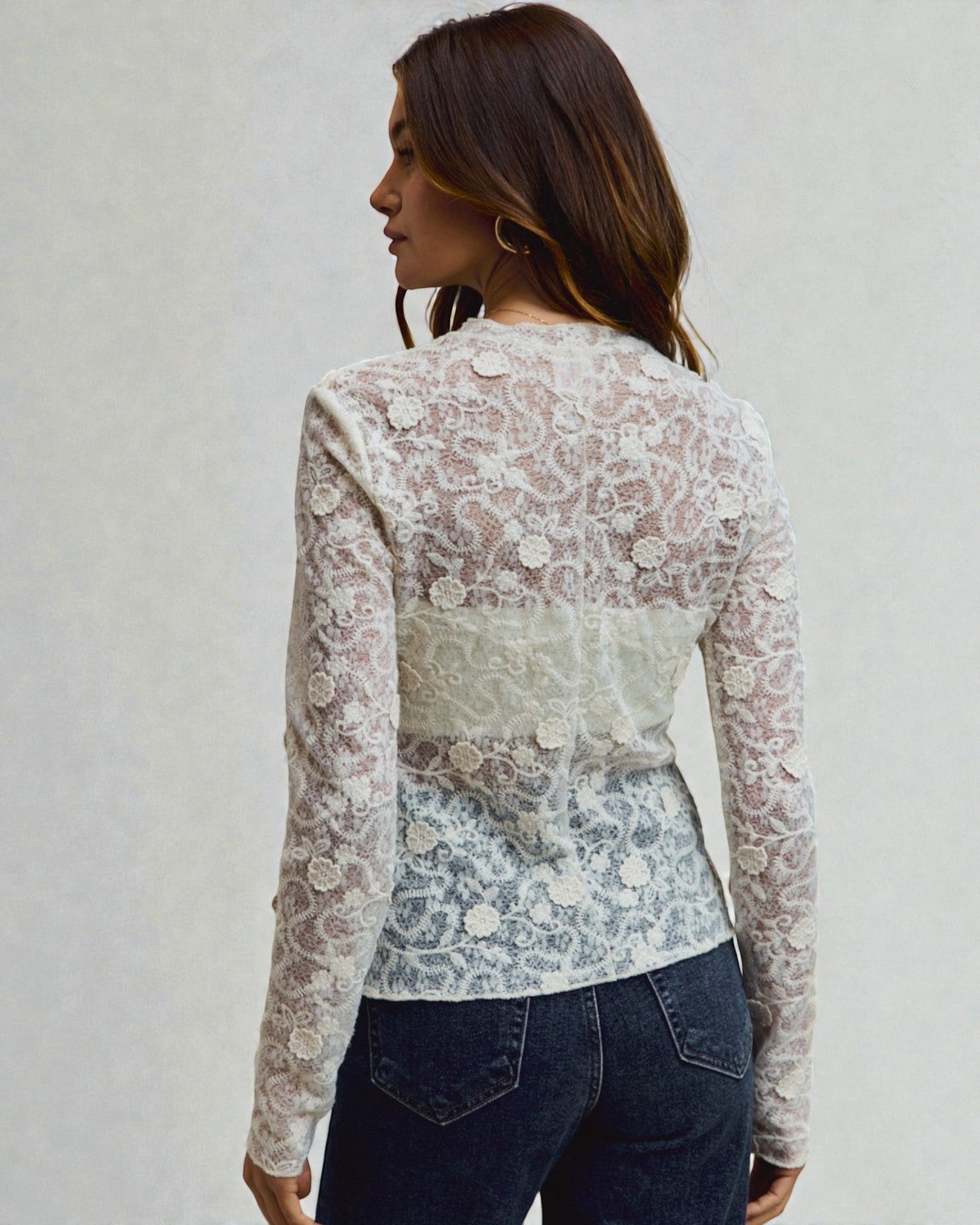 Woman wearing a floral lace top with a plain background