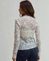 Woman wearing a floral lace top with a plain background