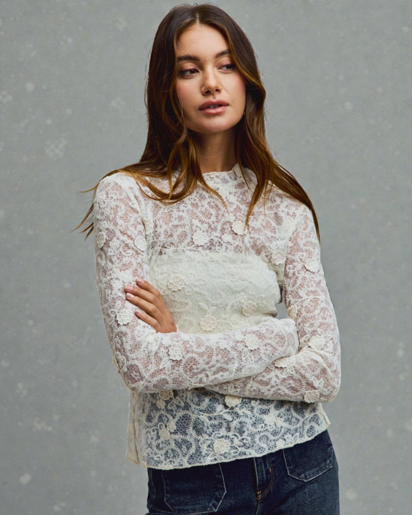 Woman wearing a white lace top with a plain background