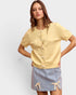 Woman wearing a yellow top and denim skirt with bow details on a light gray background