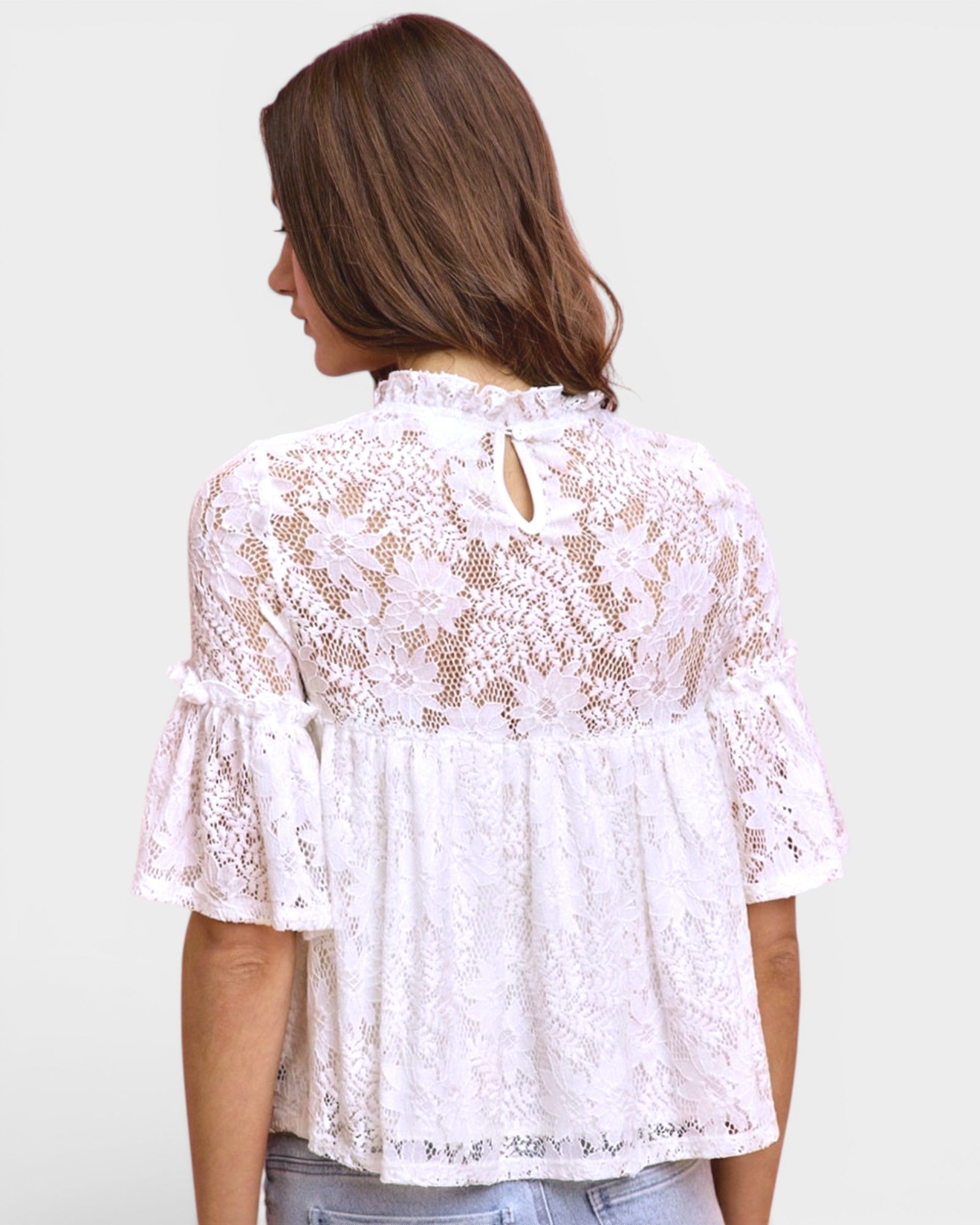White lace blouse worn by a person on a plain background