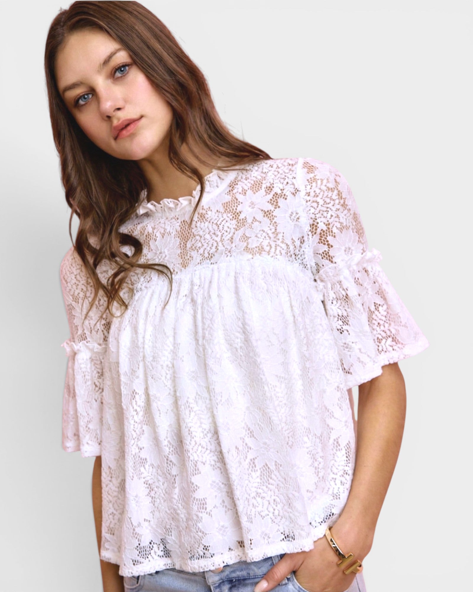 Woman wearing a white lace blouse against a plain background