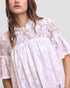 White lace top worn by a person on a plain background