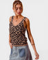 Woman wearing a leopard print tank top and denim skirt on a plain background