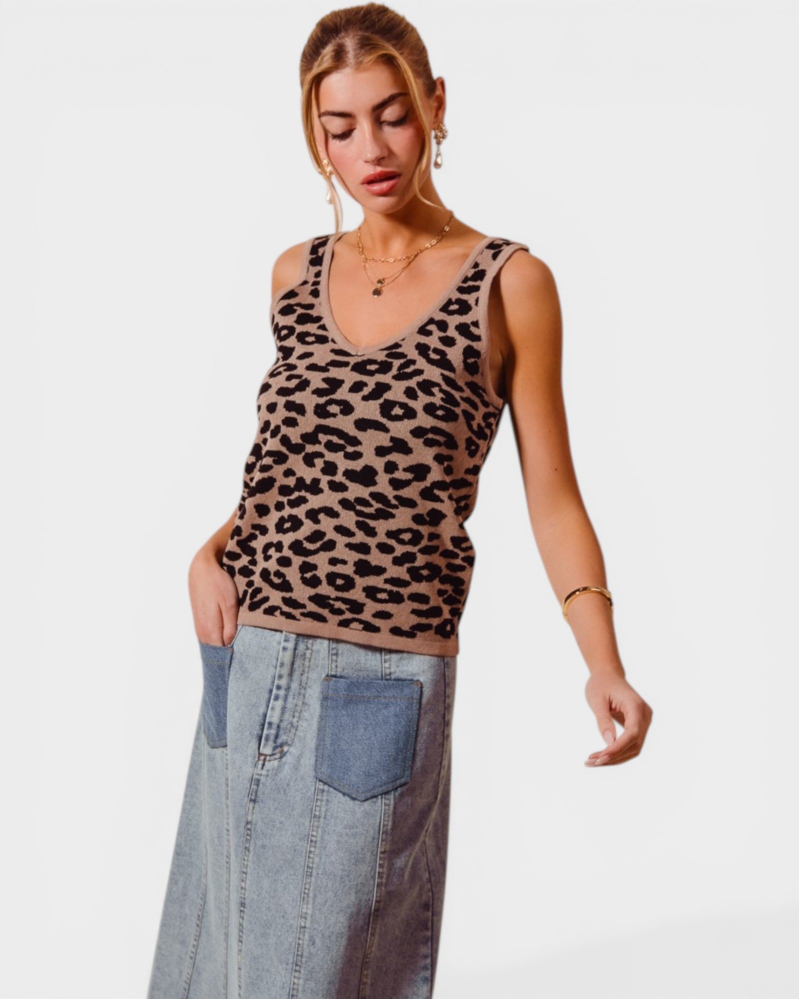 Woman wearing a leopard print tank top and denim pants on a white background