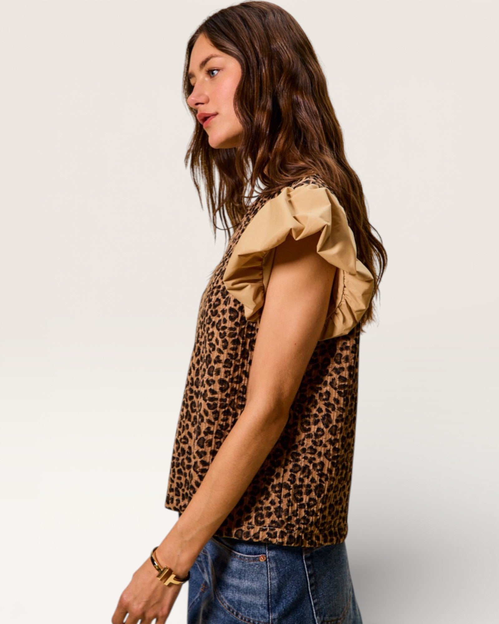 Woman wearing a leopard print top with ruffled sleeves on a plain background