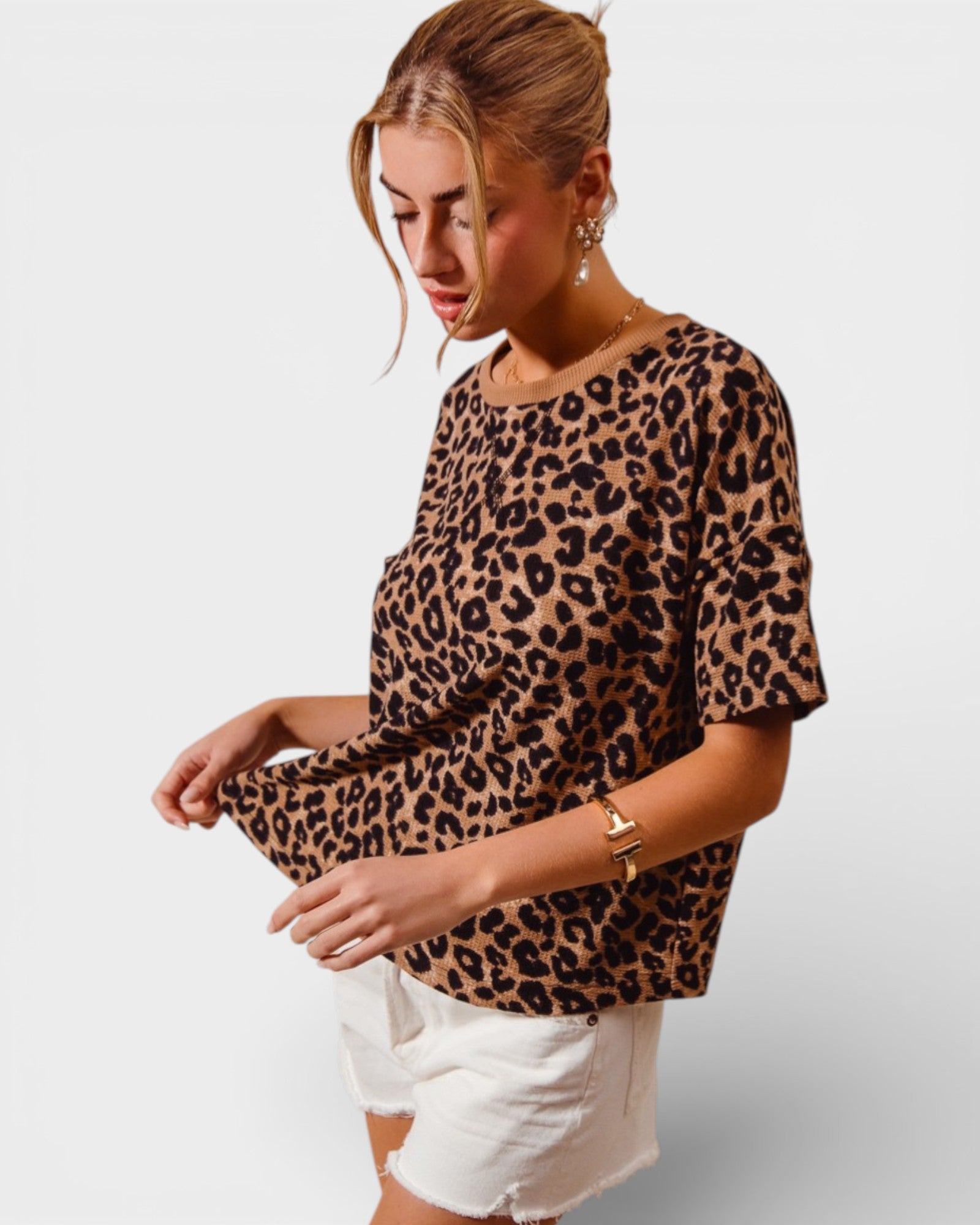 Woman wearing a leopard print top and white shorts on a plain background