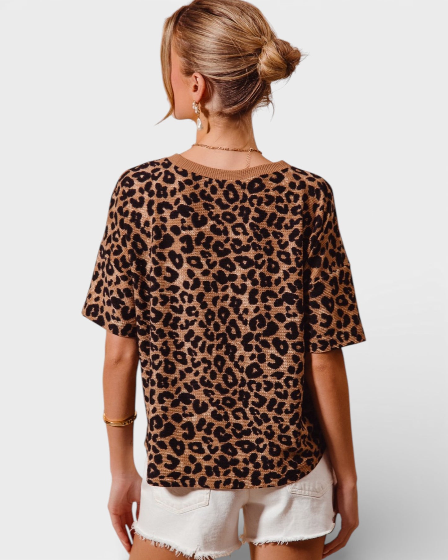 Person wearing a leopard print top and white shorts on a plain background