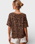 Person wearing a leopard print top and white shorts on a plain background
