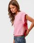 Woman wearing a pink sweater with red accents on a white background