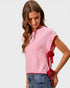 Woman wearing a pink sweater with red bow details on a white background
