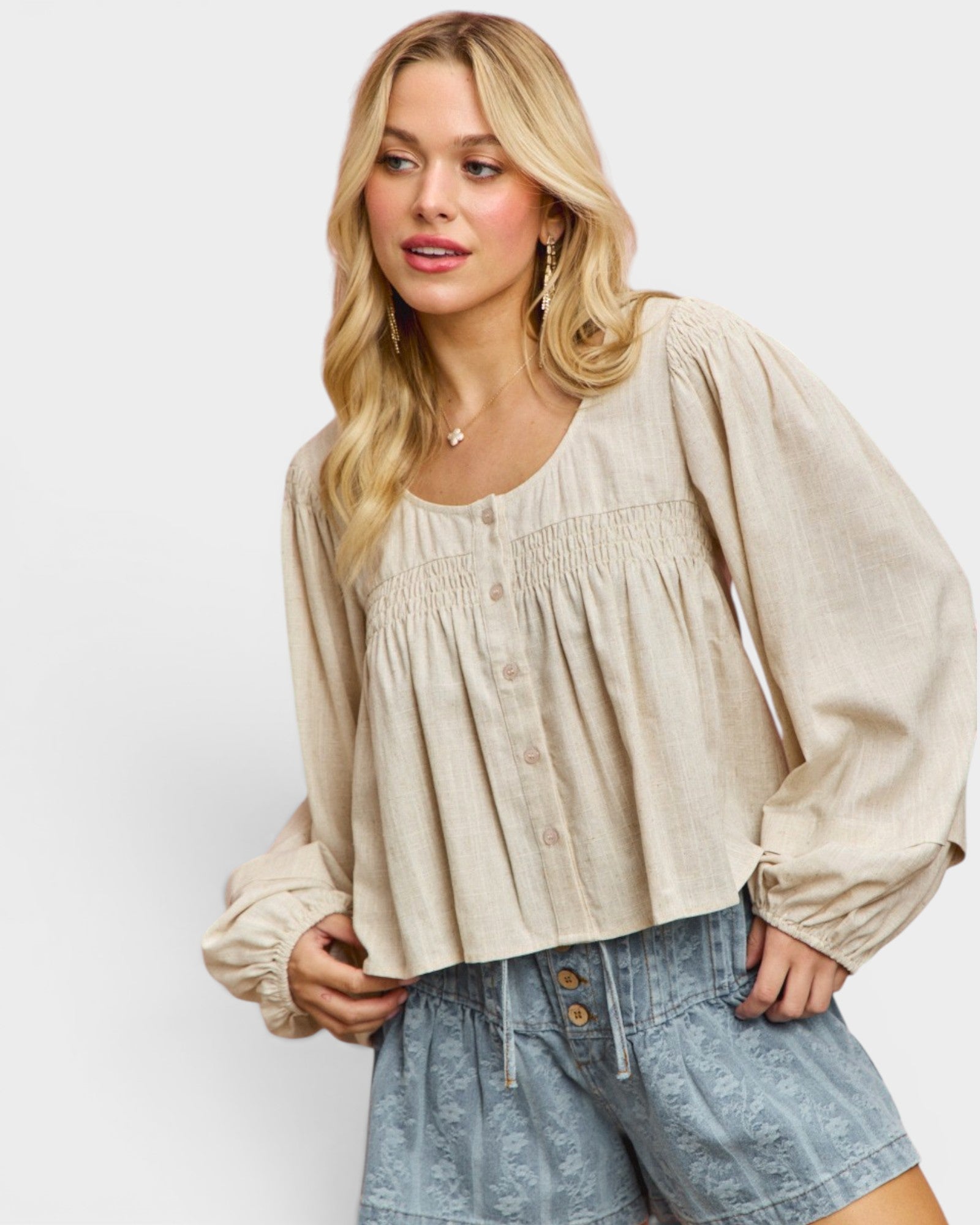 Woman wearing a beige blouse and denim shorts on a white background