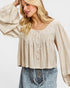 Woman wearing a beige blouse with long sleeves and blue jeans on a white background