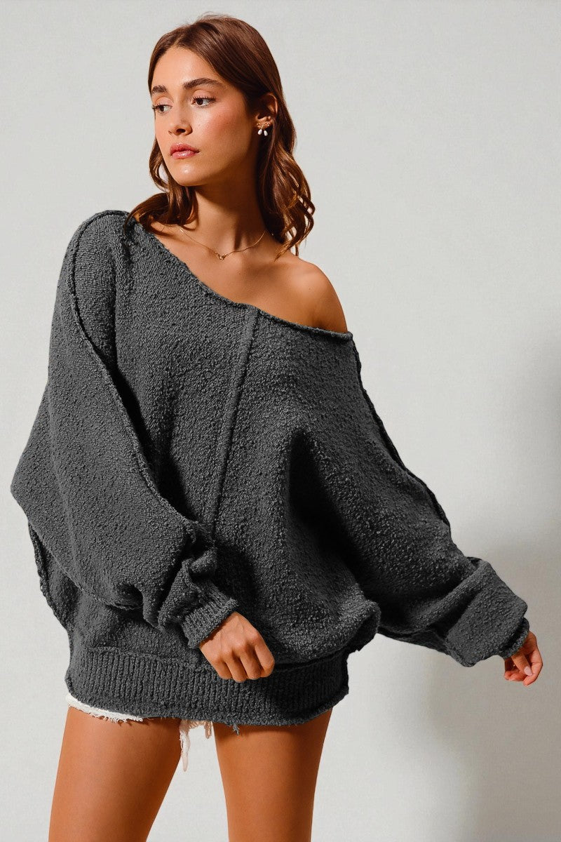 Woman wearing a gray oversized sweater against a plain background