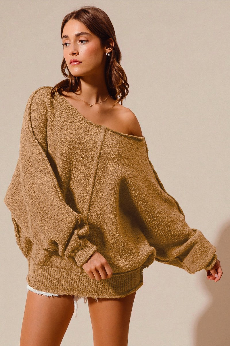 Woman wearing a beige oversized sweater against a plain background