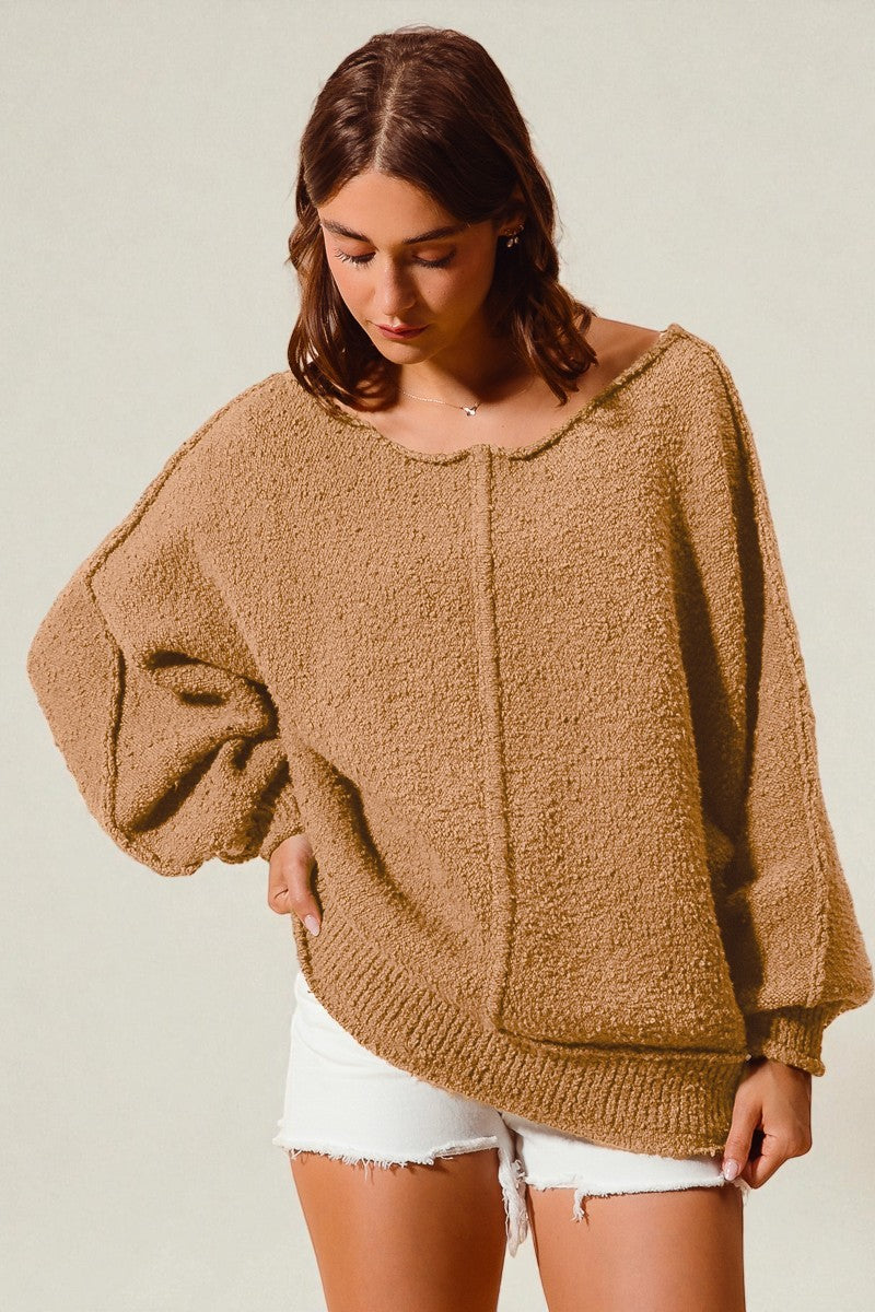 Woman wearing a brown fuzzy sweater with a neutral background
