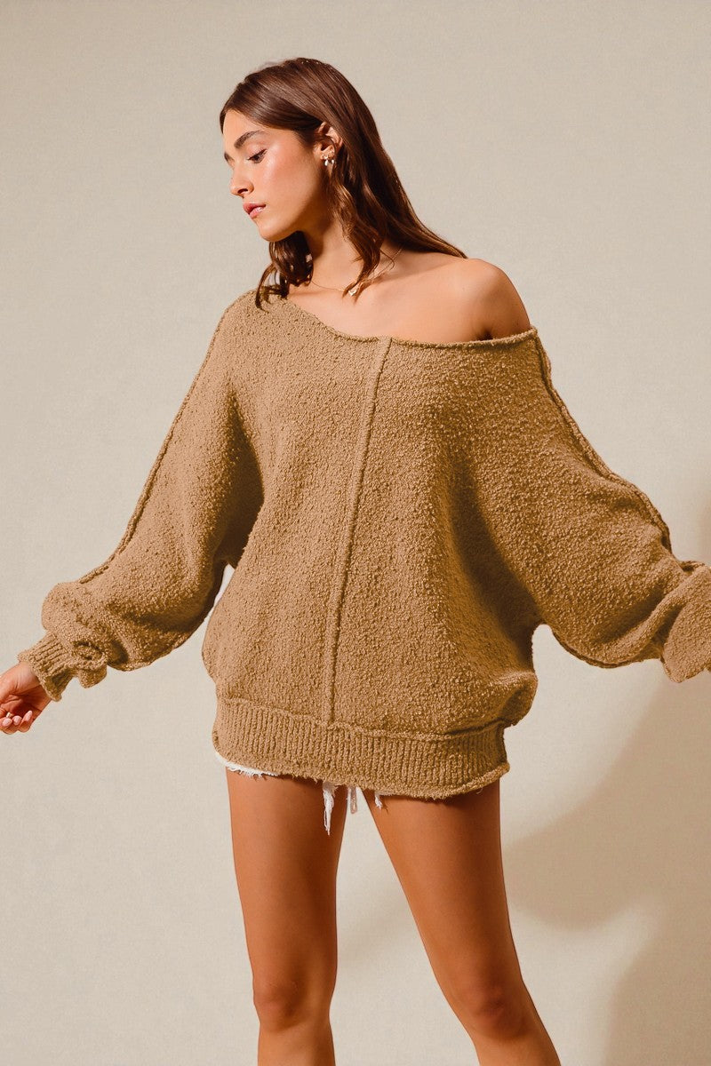 Woman wearing a beige sweater with a plain background