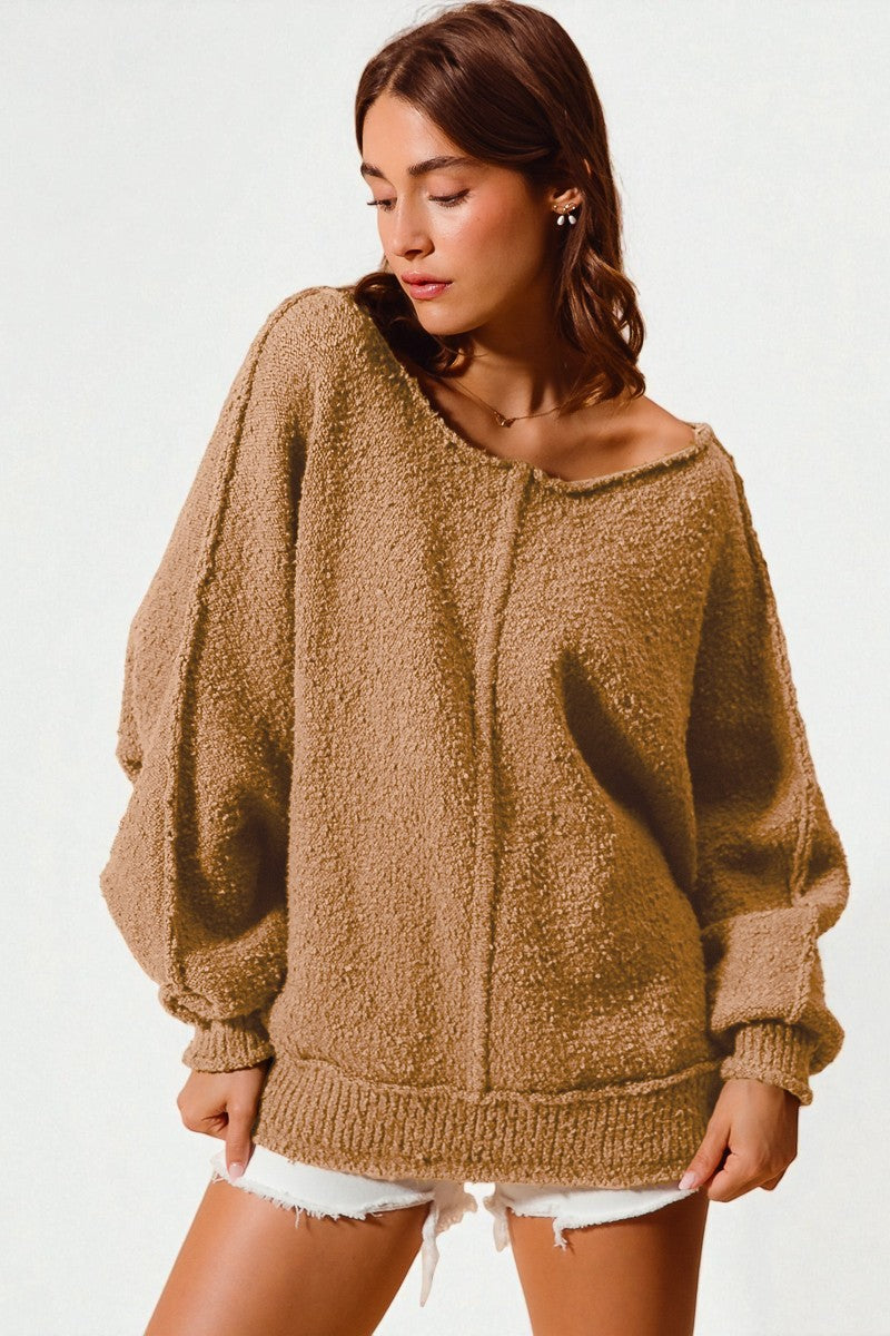 Woman wearing a brown fuzzy sweater with white shorts on a plain background