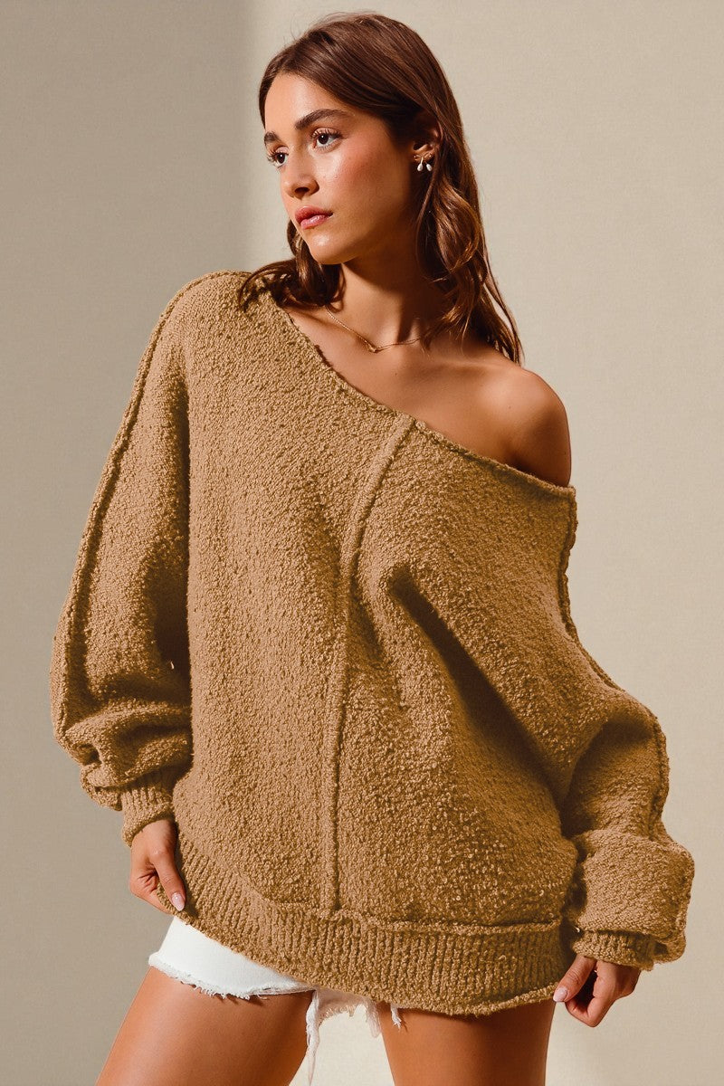 Woman wearing a brown off-shoulder sweater against a beige background