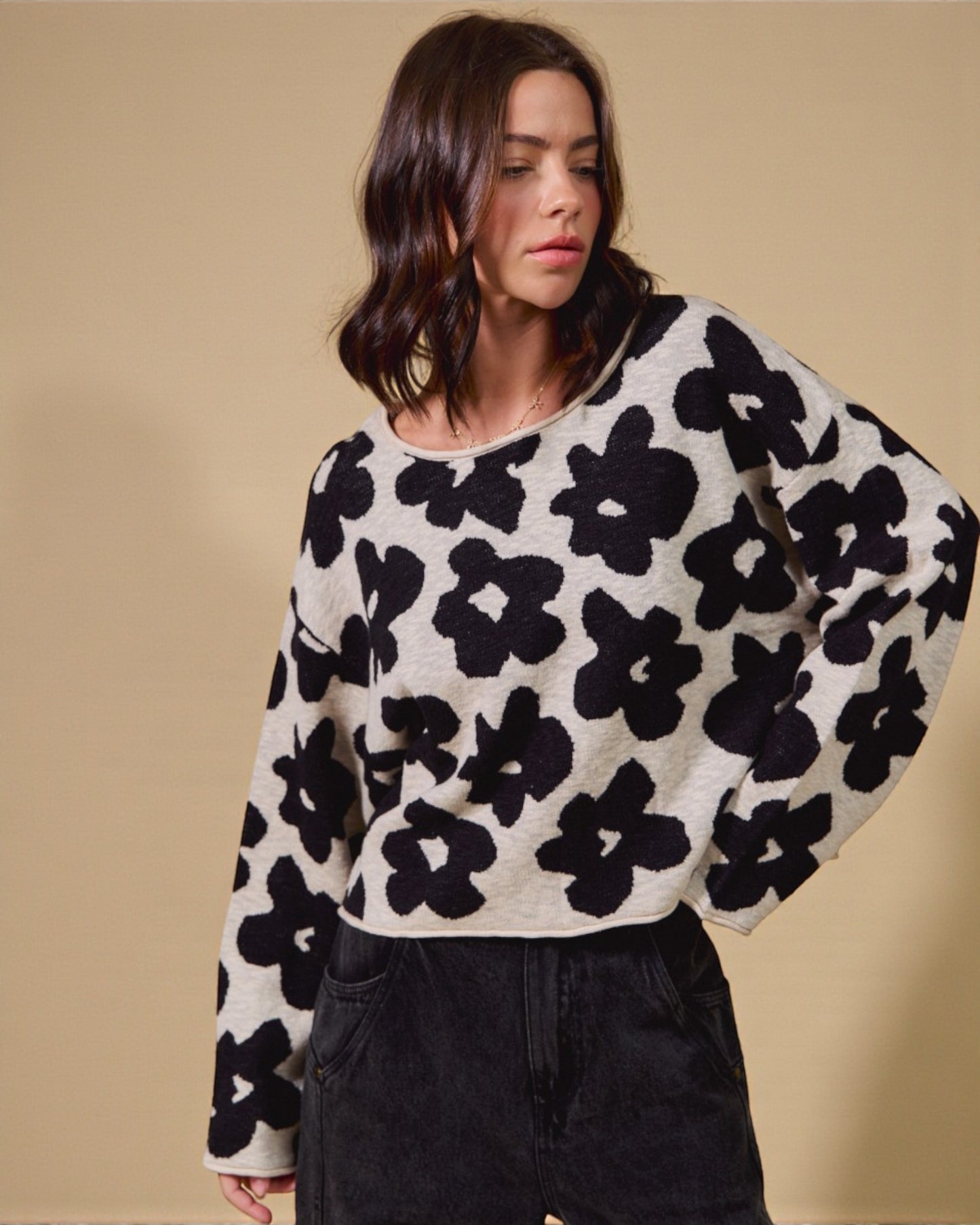 Woman wearing a black and white floral patterned sweater against a beige background