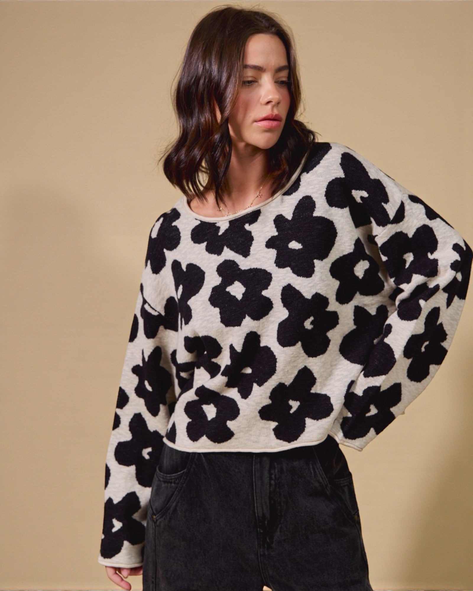Woman wearing a black and white floral patterned sweater against a beige background