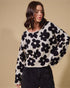 Woman wearing a black and white floral patterned sweater against a beige background