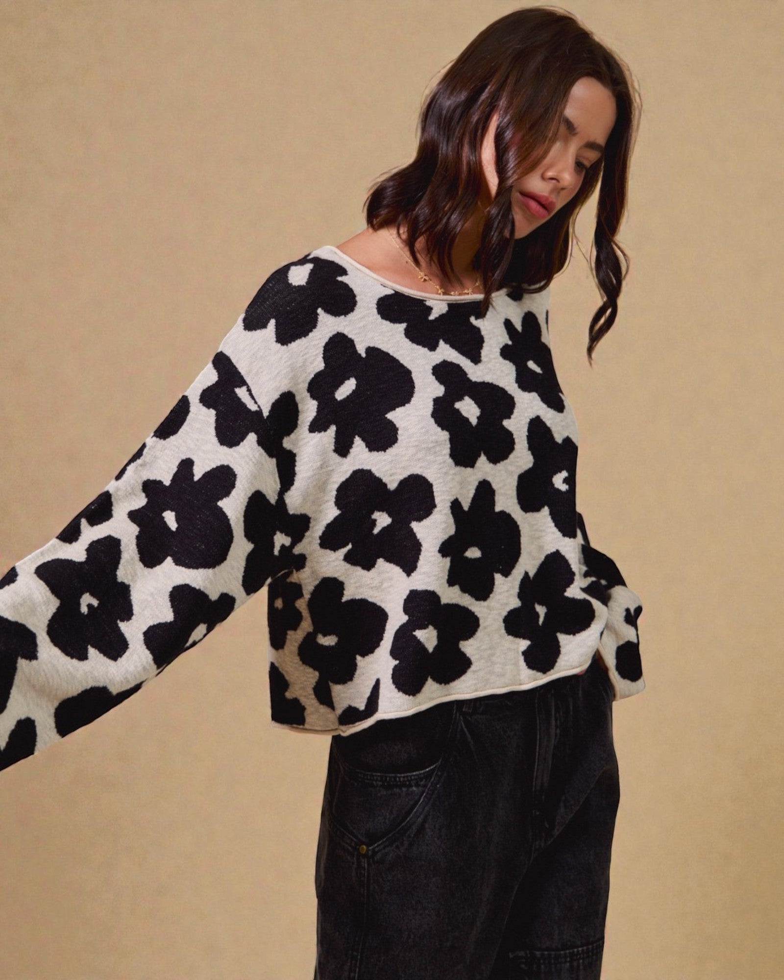 Woman wearing a black and white floral patterned sweater against a beige background