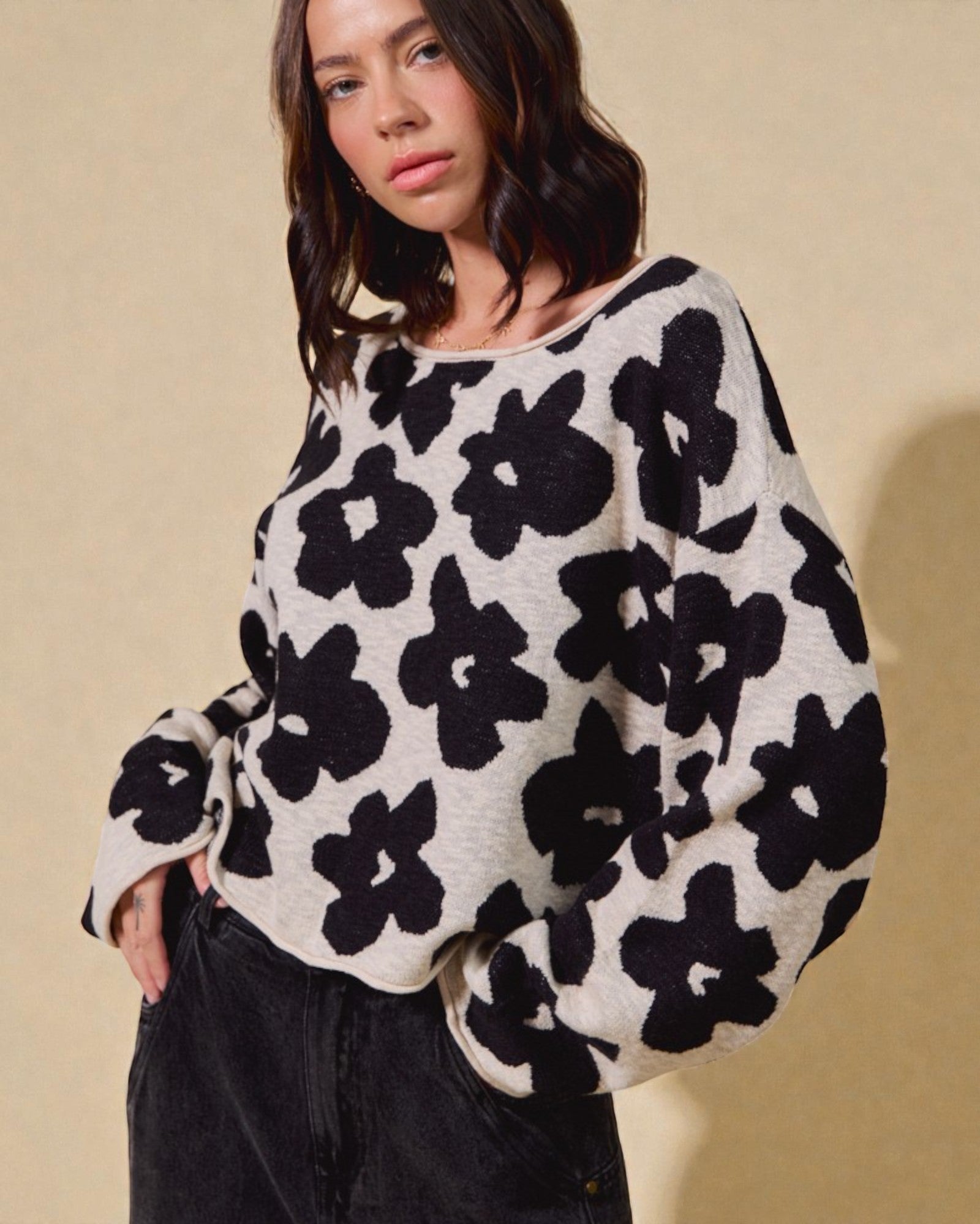 Woman wearing a black and white floral patterned sweater against a beige background