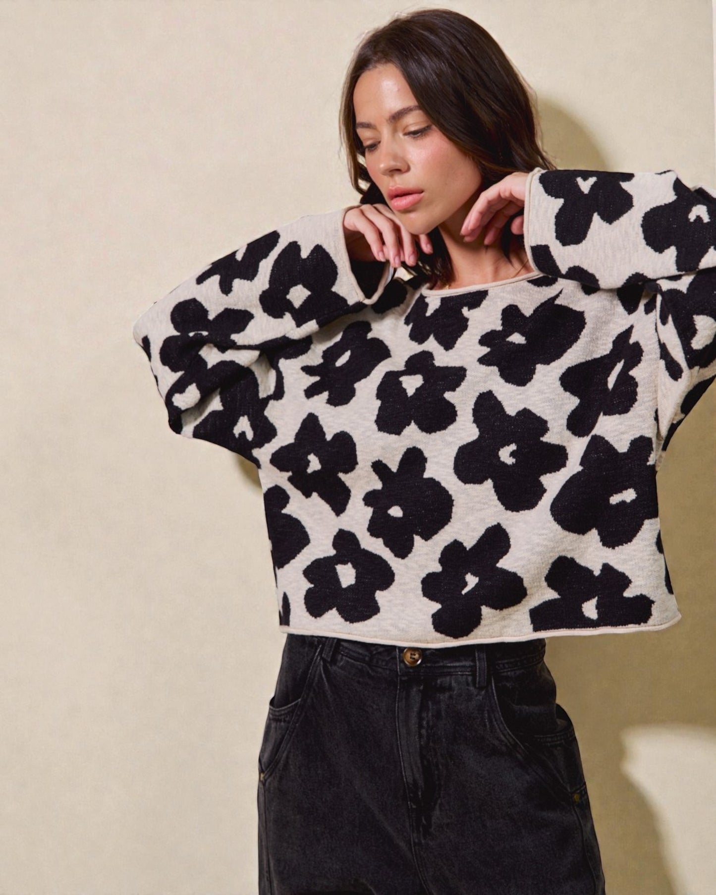 Woman wearing a black and white floral patterned sweater against a beige background