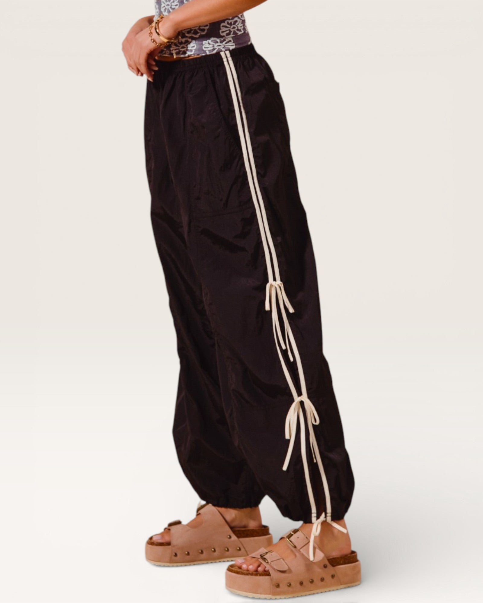 Black pants with white drawstrings and stripes on a plain background