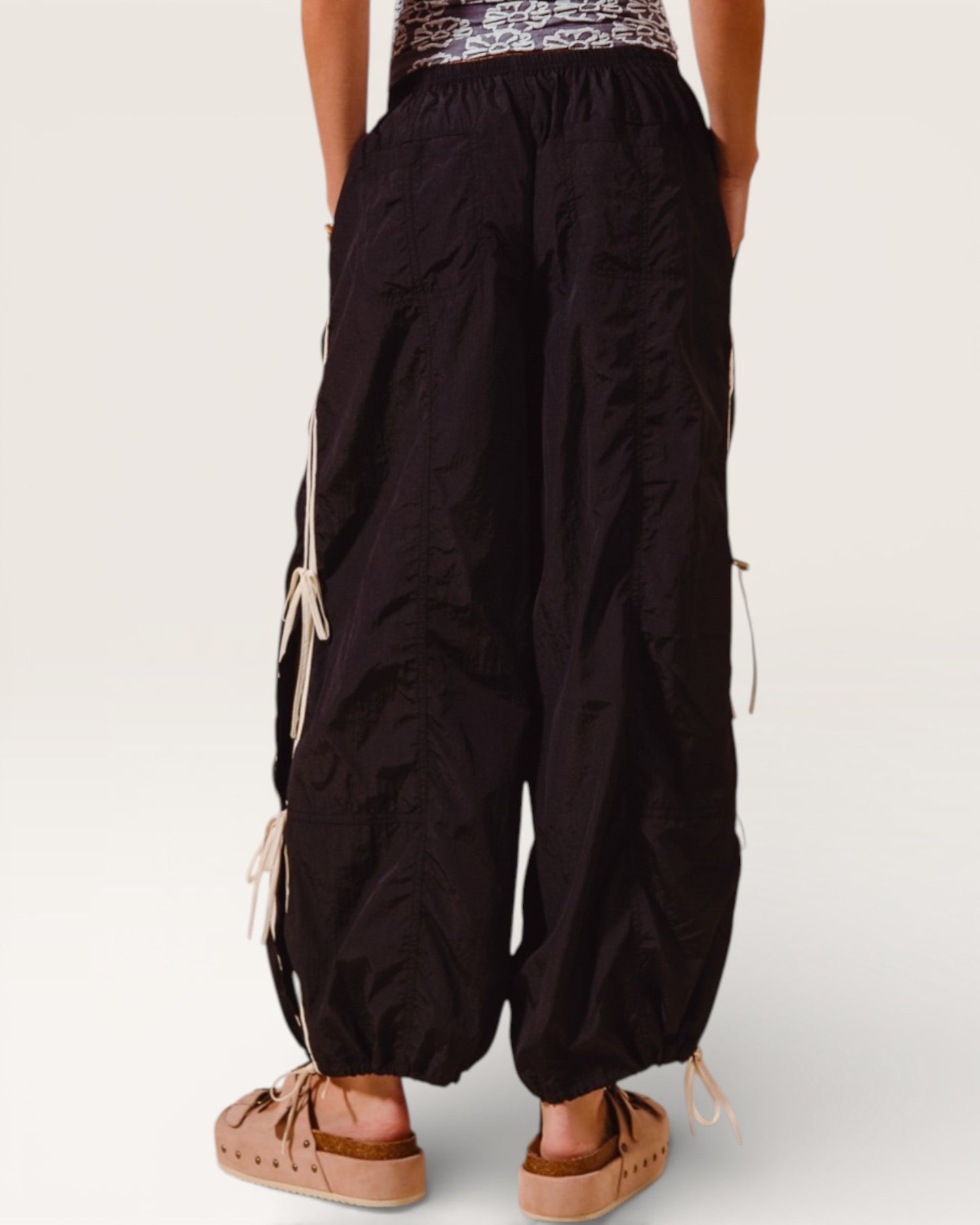 Black wide-leg pants with white drawstrings worn by a person on a plain background