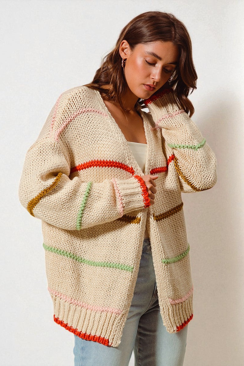 Woman wearing a beige knitted cardigan with colorful trim on a white background