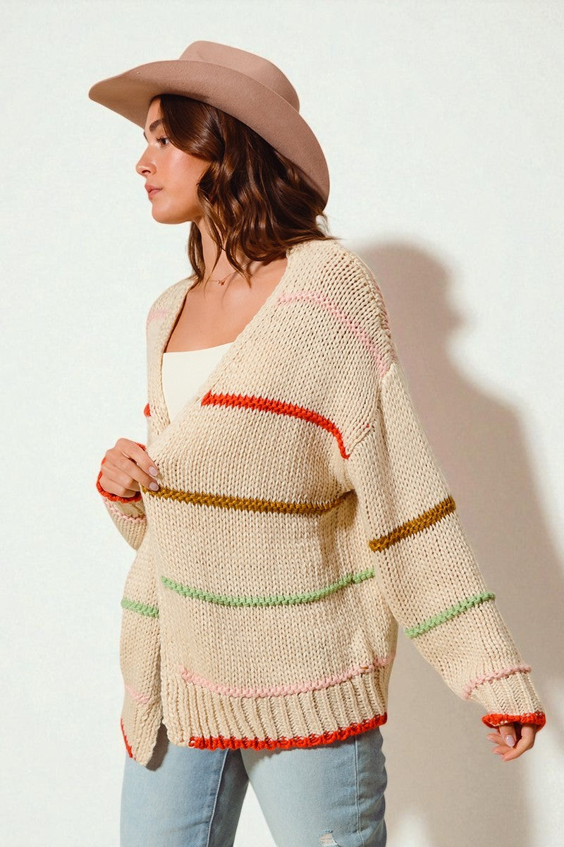 Woman wearing a beige cardigan with colorful stripes on a white background