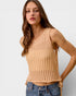 Woman wearing a beige knitted tank top against a plain background