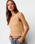 Woman wearing a beige ribbed tank top against a plain background