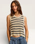 Woman wearing a striped sleeveless top and denim pants on a plain background